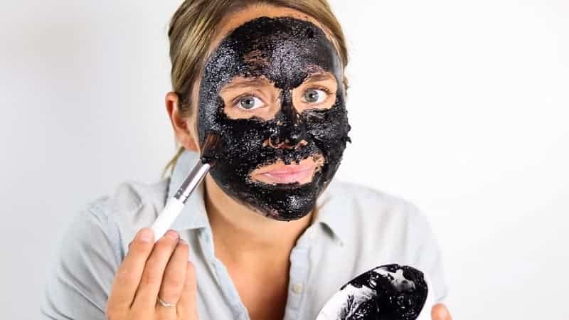 Brushing a homemade charcoal mask onto the face.