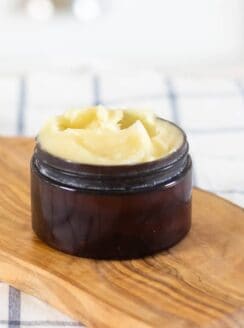 face cream in small amber container on wood cutting board