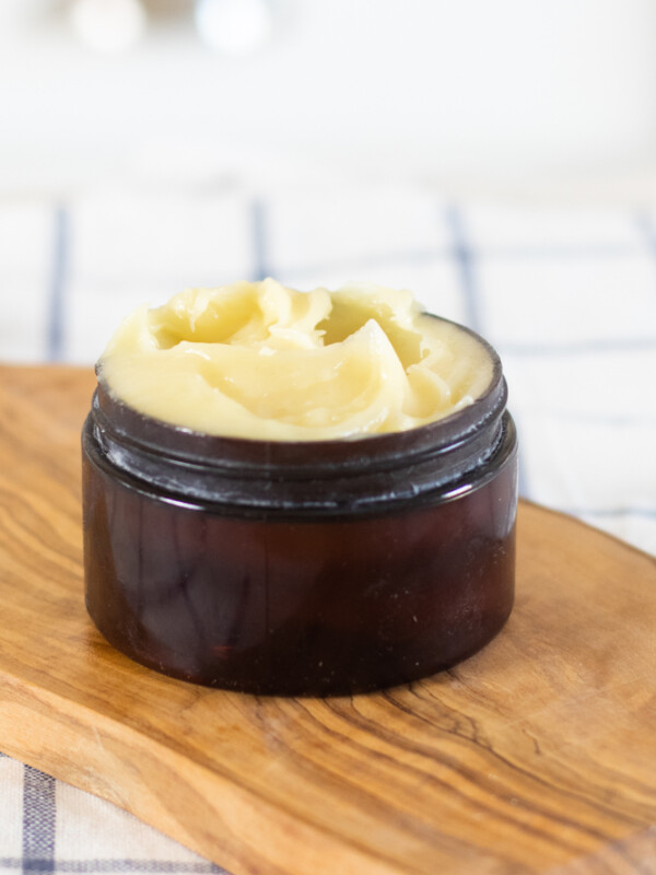 face cream in small amber container on wood cutting board