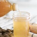 Pouring apple cider vinegar into mason jar.