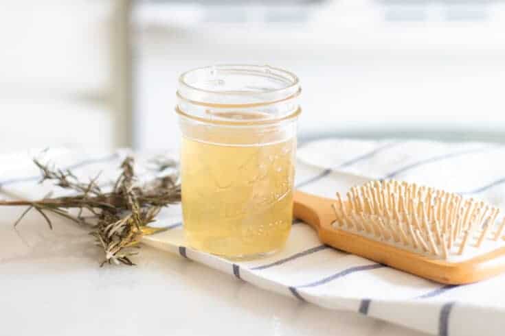 Apple cider hair rinse in mason har with fresh rosemary behind it.