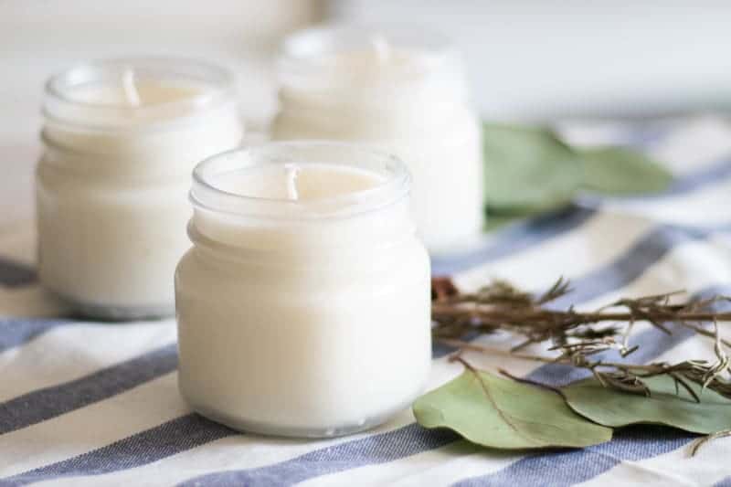 DIY Christmas essential oil candles in glass jars on decorative towel