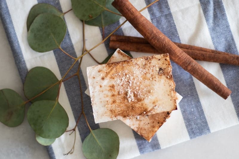 Homemade cinnamon soap bar on white and blue tea towel.