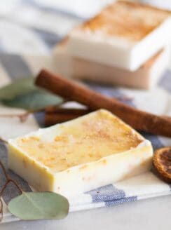 orange cinnamon soap bar with cinnamon sticks in background