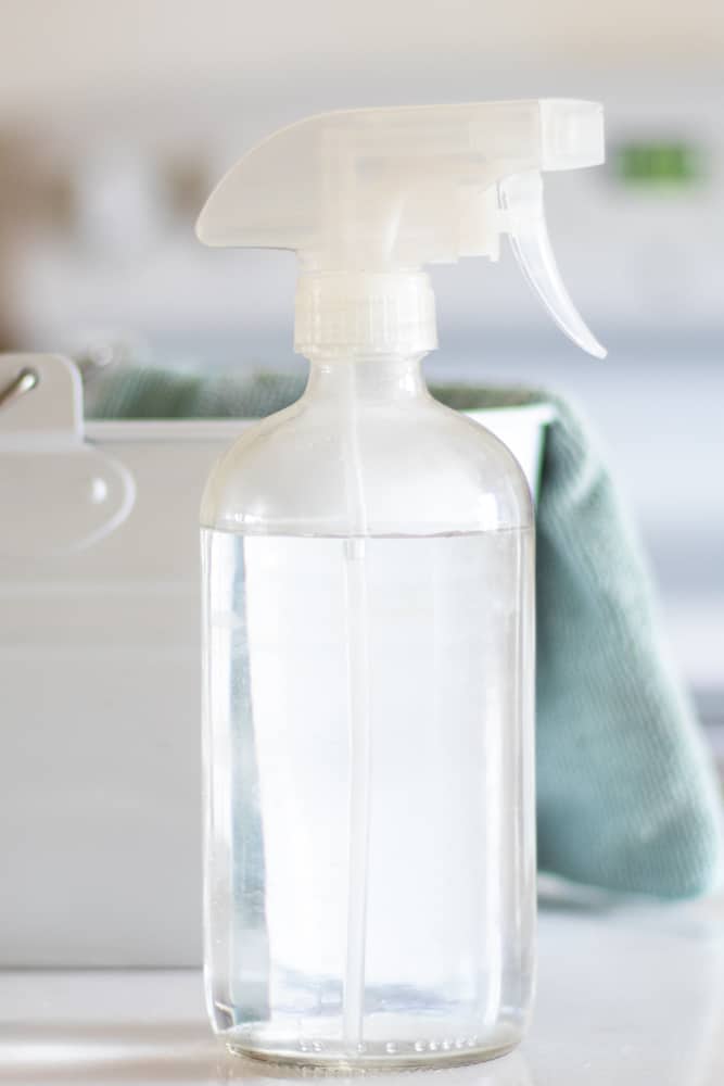 shower cleaner in glass spray bottle on white marble counter