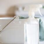 White cleaning caddy with non toxic spray bottle and blue cloth.