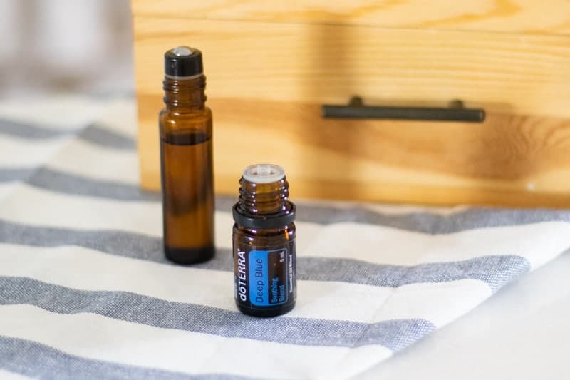 deep blue essential oil and homemade deep blue rollerball blend in front of wooden essential oil storage box