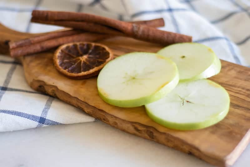 apple and orange slices on wooden cutting board 