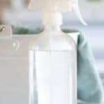 clear glass spray bottle with green cleaning towel