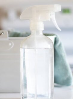 clear glass spray bottle with green cleaning towel
