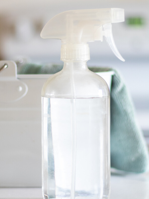 clear glass spray bottle with green cleaning towel