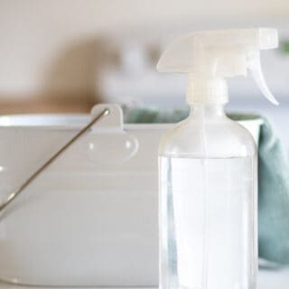 glass spray bottle in front of white cleaning caddy