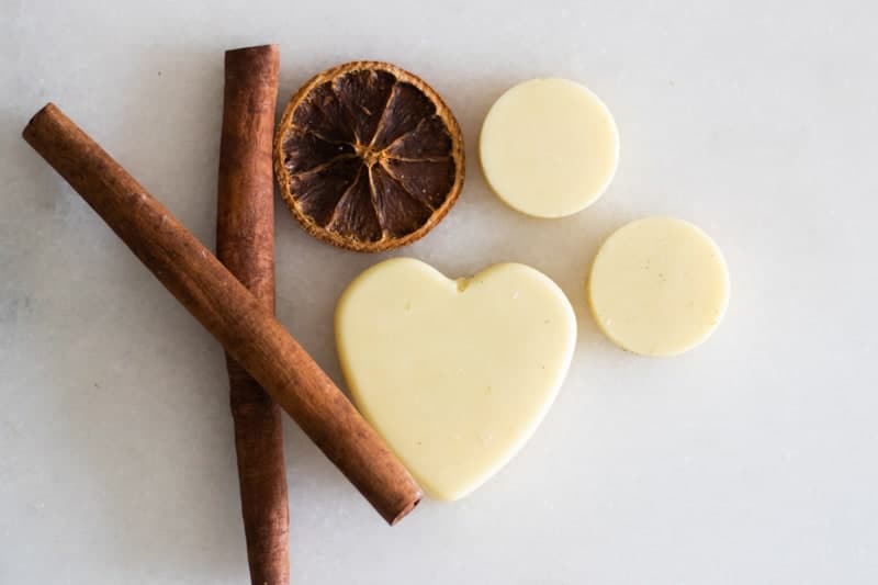 homemade wax air freshener hearts on white marble with cinnamon sticks and dried orange slice. 