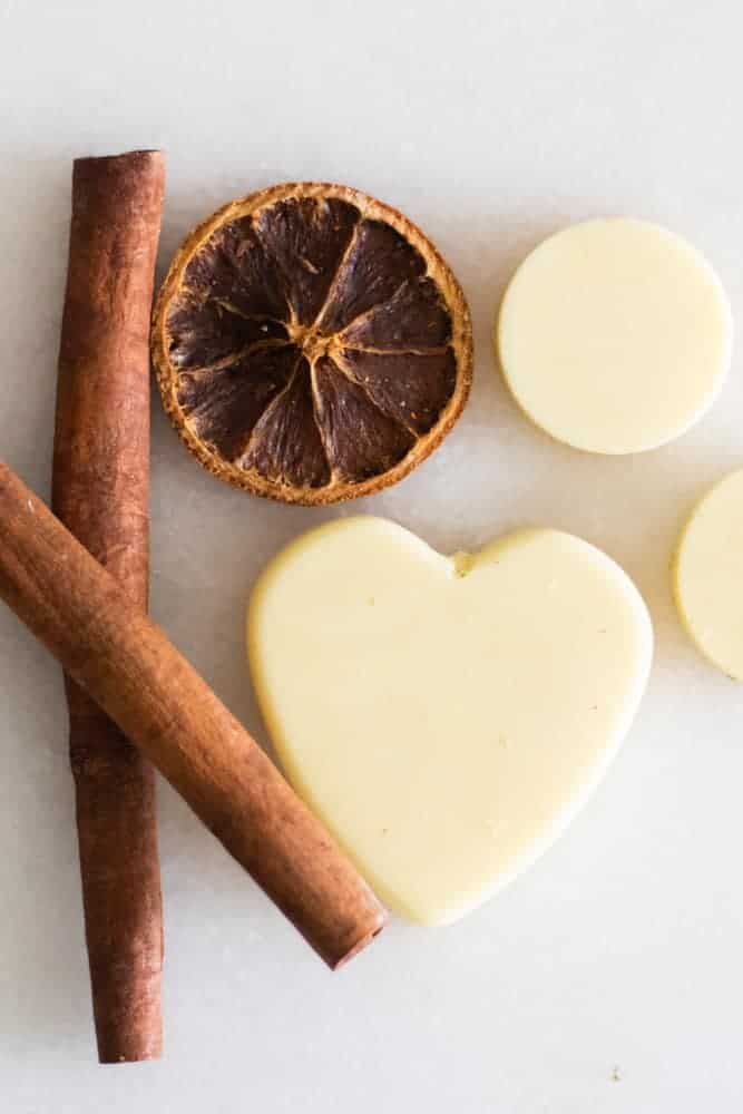 soy wax scented sachets on white marble with cinnamon sticks and orange slice