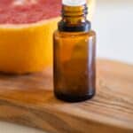 essential oil bottle in front of grapefruit