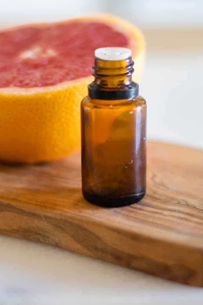 essential oil bottle in front of grapefruit