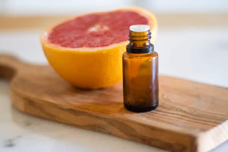 grapefruit essential oil on wooden cutting board with grapefruit