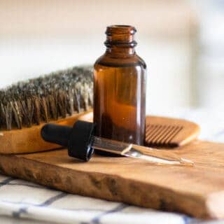 beard oil in a dropper bottle on wooden cutting board