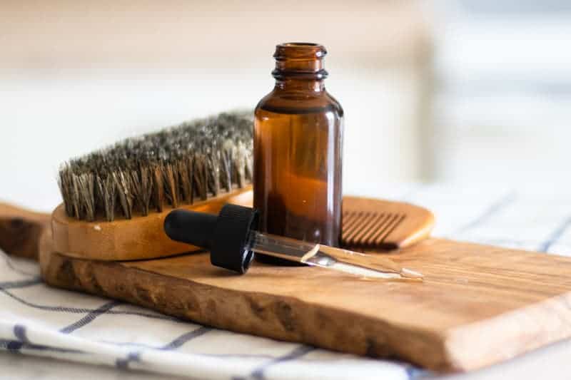 beard oil in a dropper bottle on wooden cutting board 