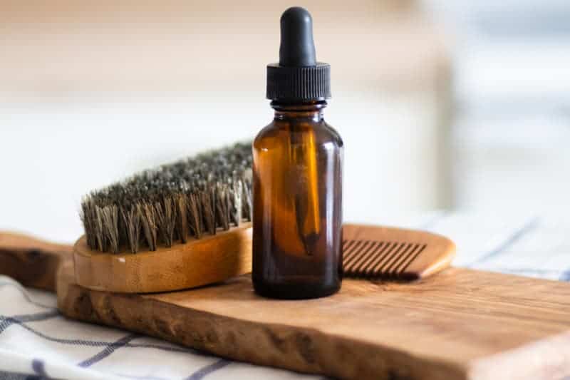 homemade beard oil in amber dropper bottle on wooden board