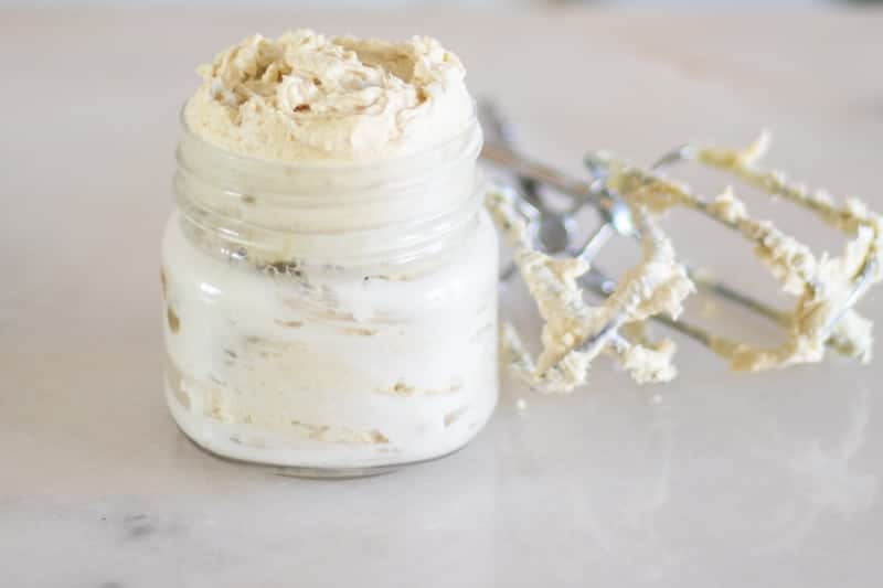 Finished product of glowing skin body butter with mixers next to it on white marble.