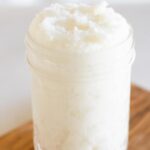 Whipped sugar scrub in mason jar on wooden board.