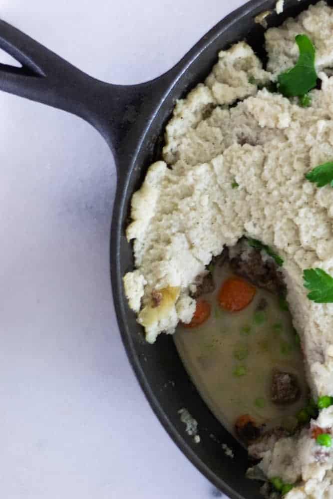 dairy free shepherd's pie topped with cauliflower mashed potatoes in cast-iron skillet 