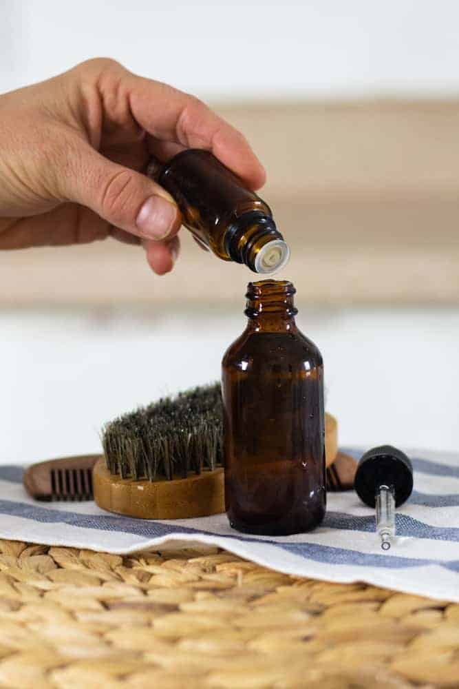 women adding drops of essential oils to homemade beard shampoo