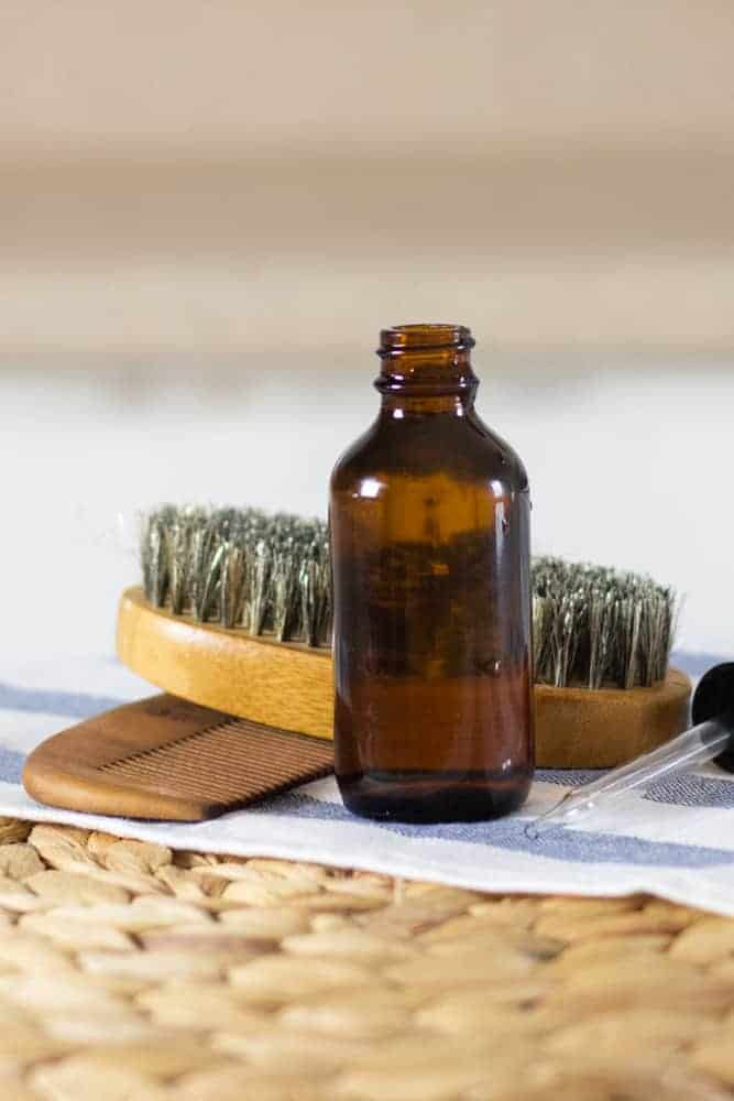 DIY beard shampoo in dropper bottle beard brush and comb behind it