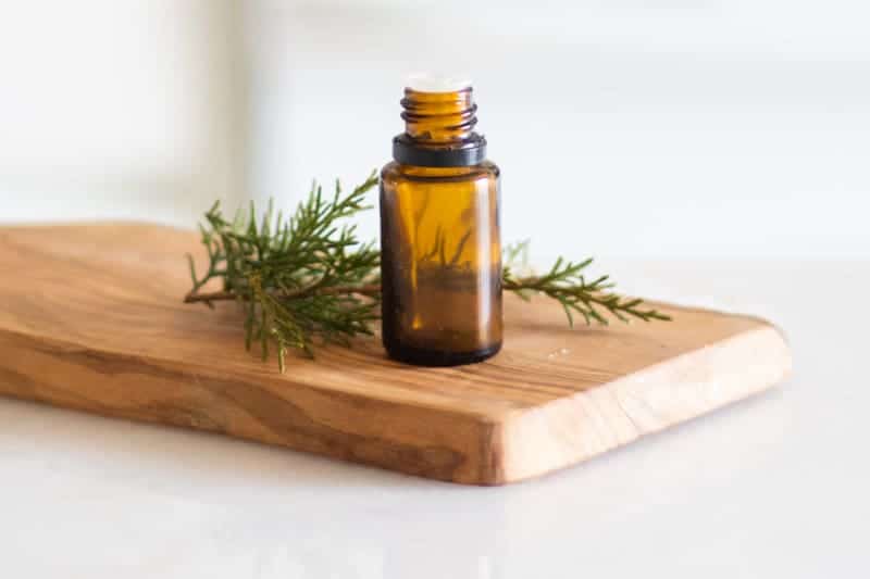 Siberian fir essential oil on wooden board with pine needles around it