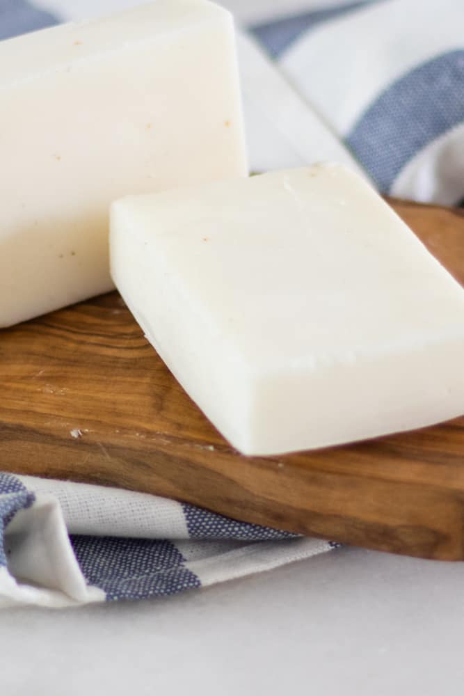 Two freshly cured plain white soap bars on blue and white tea towel.