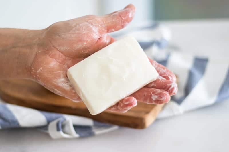 Wet and soapy tallow soap bar in palm of hand.