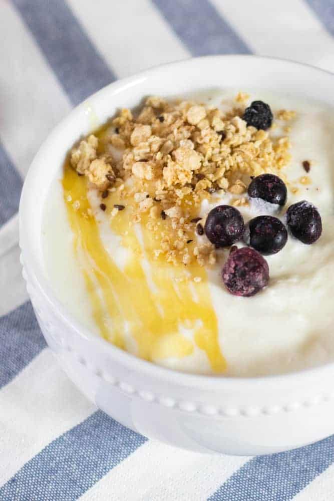 Homemade instant pot yogurt in white bowl topped with berries and granola.