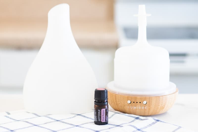 Pink pepper essential oil and white diffuser on table.