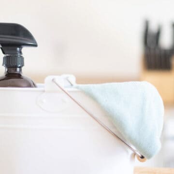 DIY all purpose house cleaner in a white cleaning bucket with a micro fiber towel.