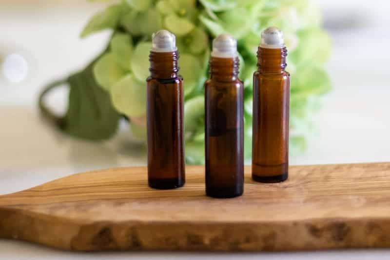 Essential oil roller bottles on wood cutting board. 