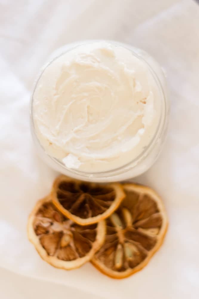 Small mason jar of homemade hand cream on white tea towel. 