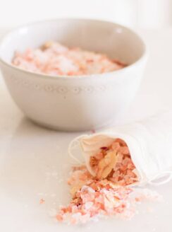 rose bath salts in small glass bowl and small muslin bag.