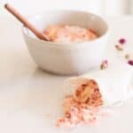 A bag of rose bath salts with a bowl in the background.
