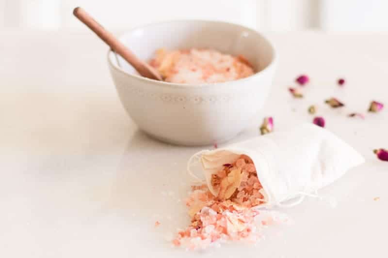 Homemade Rose bath salts in muslin bag on white marble table.