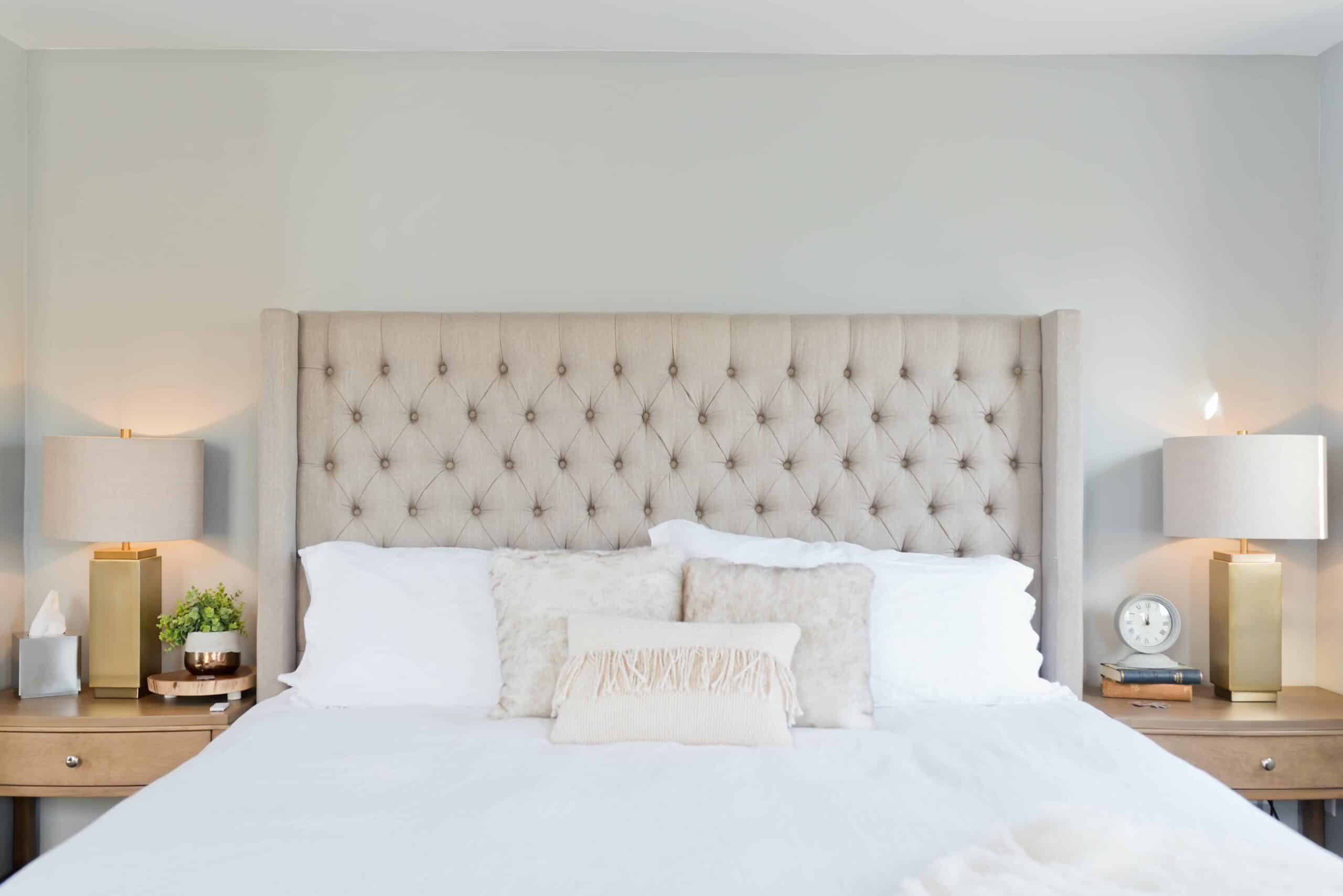 A bed with a large beadboard and bedside lamps turned on. 