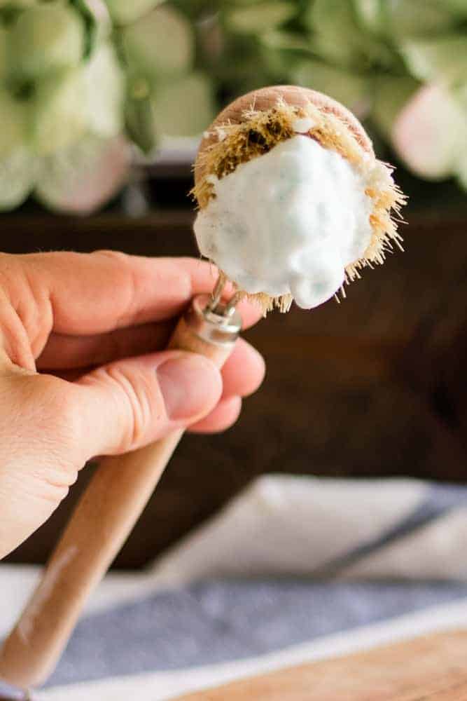 Applying foaming shave cream with a wooden applicator.