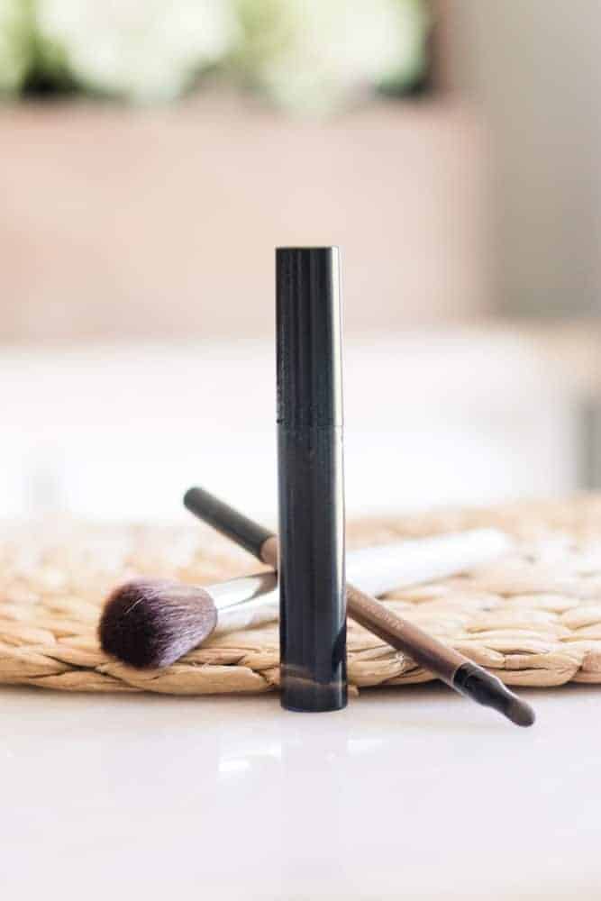 Homemade mascara in black tube sitting on white table.