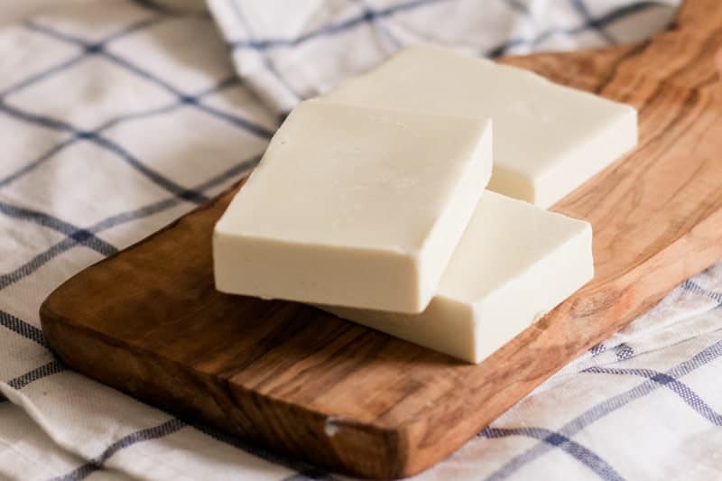 DIY sunscreen bars stacked on wooden cutting board. 