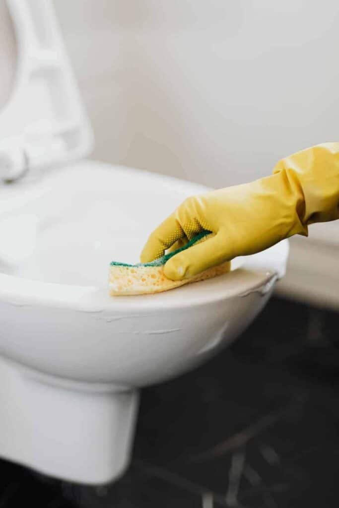 Wiping toilet clean with foaming toilet cleaner.