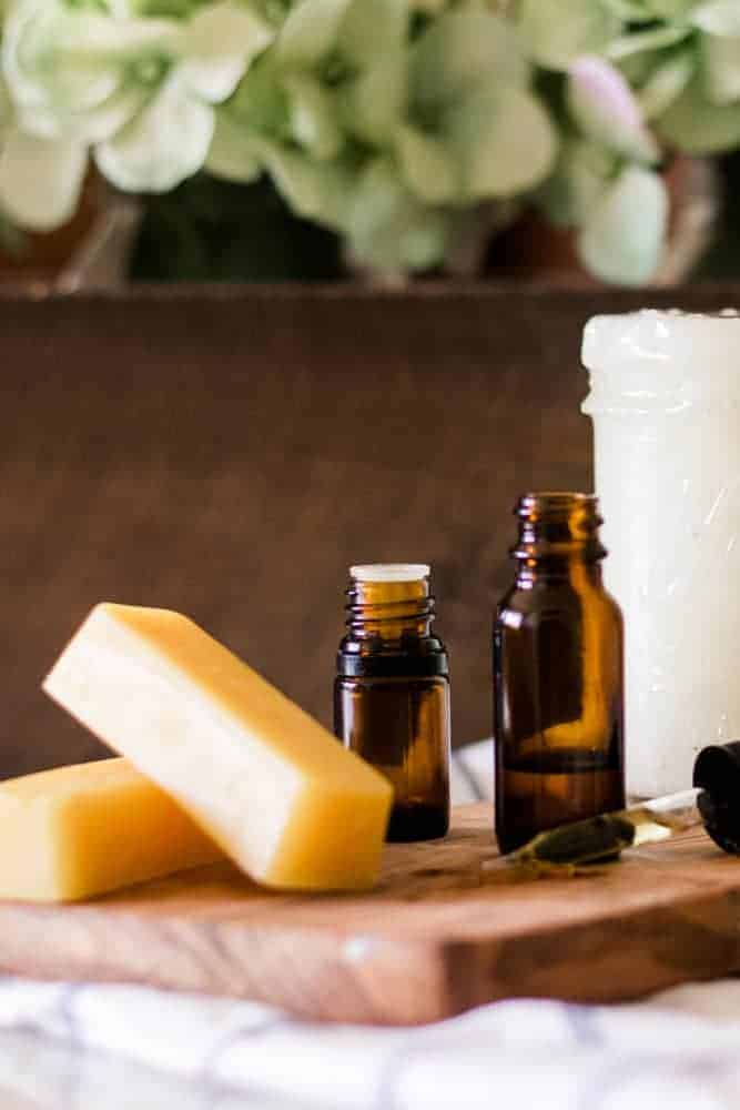 Beeswax, coconut oil, vitamin E oil, and essential oils sitting on wooden board. 