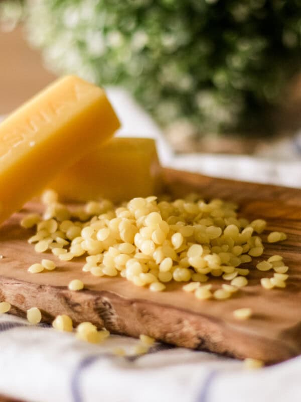 Beeswax pellets and bars on a wooden tray.
