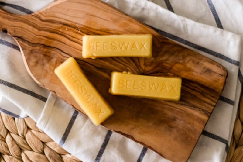 Three beeswax bars on wooden cutting board. 