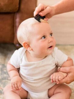 combing out cradle cap from a babys hair.