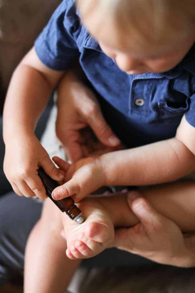 Toddler applying essential oils to the bottom of his feet.